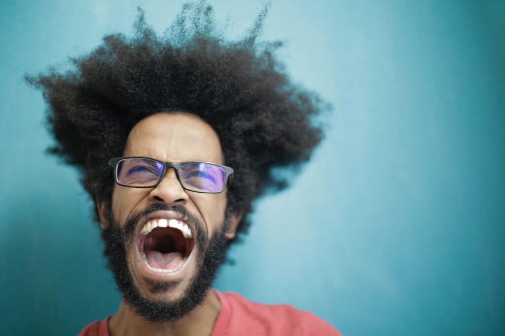 Man Standing in front of blue wall yelling - depicting the 'voice' considerations in article