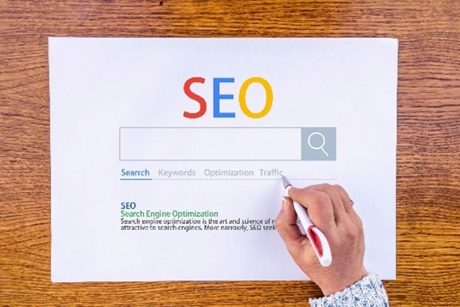 A print out of a SERP (Search Engine Results Page) with "SEO" typed in big colorful text above it.